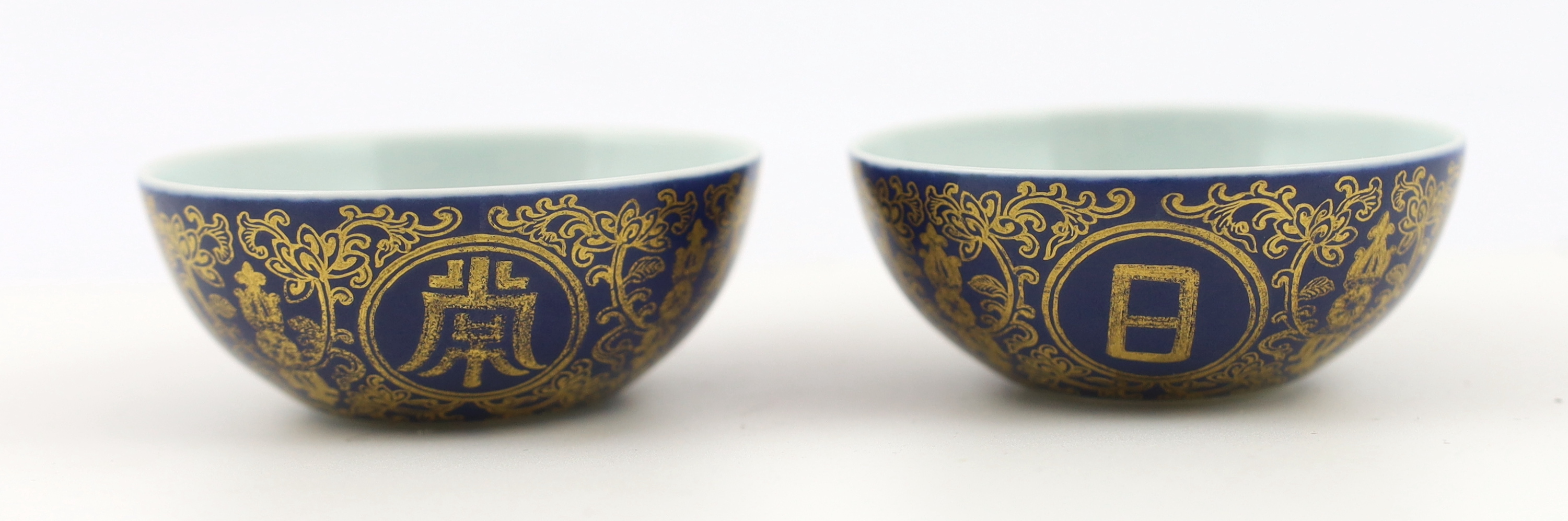 A pair of Chinese gilt decorated blue ground cups, Qianlong mark but later, one cracked